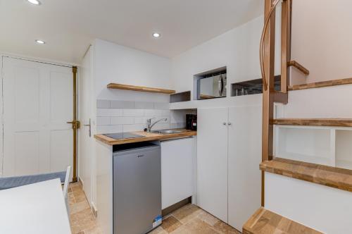 - une cuisine avec des murs blancs et des étagères en bois dans l'établissement Place Du Pin - Wifi, AC, 2 pers, à Nice