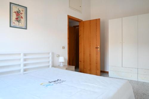 a bedroom with a white bed and a wooden door at S076 - Sirolo, bilocale in centro, con terrazzo e aria condizionata! in Sirolo