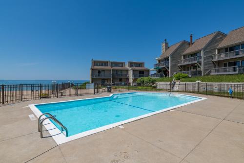 a swimming pool in front of a building with the ocean at Harbours 10- Condo with community pool in South Haven