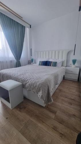 1 dormitorio con 1 cama blanca grande y suelo de madera en Cozy Modern Apartament, en Focşani