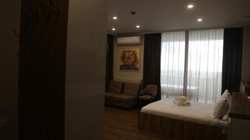a bedroom with a bed and a chair and a window at Golden Sun Kobuleti in K'obulet'i