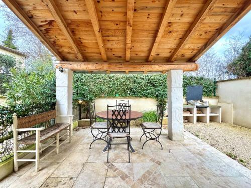 a patio with a table and chairs under a wooden pergola at Le Pigeonnier d'antan à Beaucaire,Fourques in Beaucaire