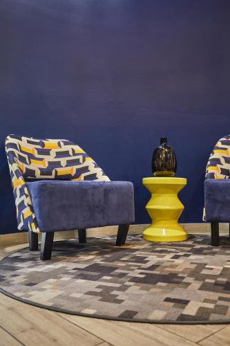 a living room with two chairs and a yellow vase at Appart'hôtel Odalys City - Paris Levallois in Levallois-Perret
