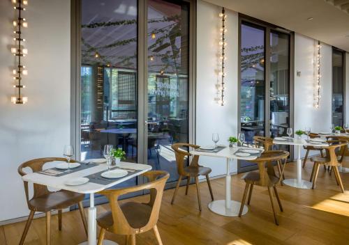 a restaurant with white tables and chairs and windows at Occidental Barcelona 1929 in Barcelona