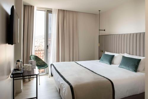 a hotel room with a bed and a large window at Occidental Barcelona 1929 in Barcelona