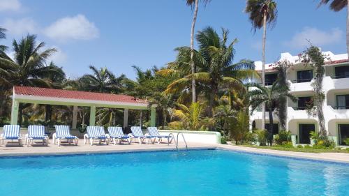 a swimming pool with chairs and a building at Hotel Club Akumal Caribe in Akumal