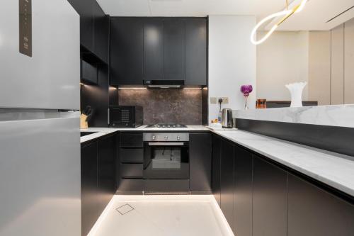 a kitchen with black cabinets and white counter tops at Samaya Holiday Homes - Family Luxury Suites in Dubai