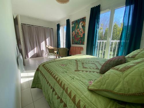 ein Schlafzimmer mit einem Bett mit einer grünen Bettdecke in der Unterkunft Maison 3 chambres, Parking, jardin, climatisation in Arles