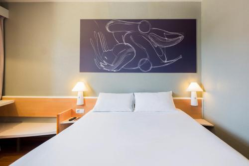 a bedroom with a large white bed with two lamps at Ibis Granada in Granada