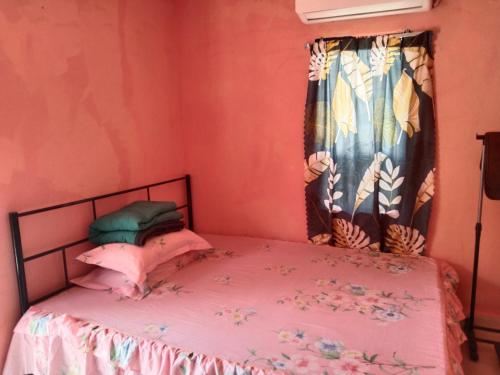 a bedroom with a bed with pink sheets and a window at Putat Gajah Villa PASIR MAS in Pasir Mas