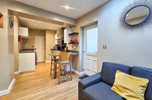 a living room with a blue couch and a kitchen at Valley Mount House & Apartment in Harrogate