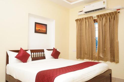 um quarto com uma cama com almofadas vermelhas e uma janela em Janz Marina Bay em Pondicherry