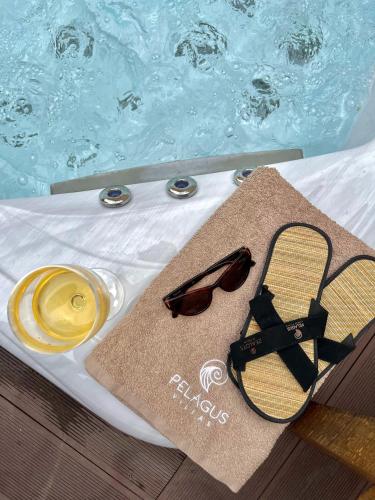 a pair of sunglasses and a towel next to a swimming pool at Pelagus Luxury Villas in Polykhrono