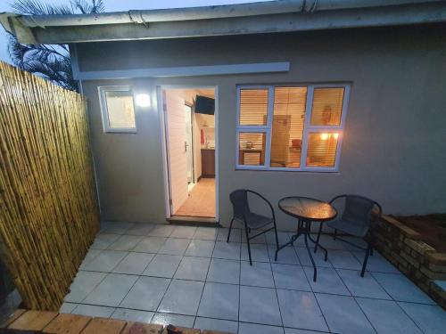 un patio con tavolo, sedie e una casa di Willow's Corner-Just like home! a Durban