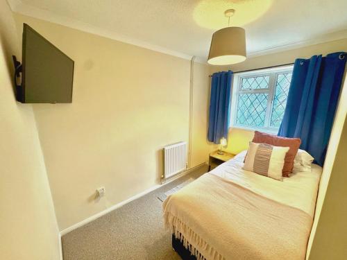 キドリントンにあるHomely 2 bedroom house, parkingのベッドルーム1室(青いカーテン、窓付)