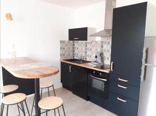a kitchen with black cabinets and a table and stools at charmante maison de ville 4 pers wifi in Châteauroux