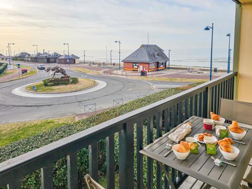 une table avec de la nourriture sur un balcon avec vue sur l'océan dans l'établissement Villers Plage 1, à Villers-sur-Mer