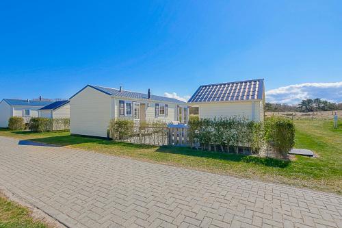a house with a fence in front of it at Chalet Luttikduin Nr 22 - Callantsoog aan Zee in Callantsoog