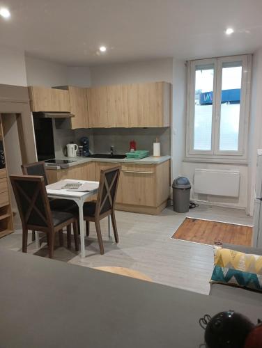 une cuisine avec une table et des chaises dans une cuisine dans l'établissement Grand Studio chambre séparée, à Arpajon-sur-Cère