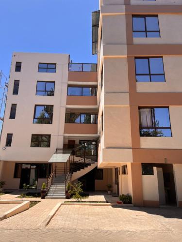 an apartment building with a staircase in front of it at Koselig Studio Apartment with Swimming Pool in Naro Moru