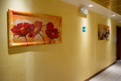 a painting of red flowers on a wall at Hotel New Aurora Venice in Marghera