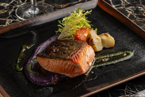 a black plate with a piece of meat and vegetables at InterContinental - Los Angeles Downtown by IHG in Los Angeles