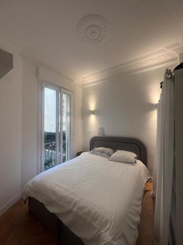- un lit blanc dans une chambre avec fenêtre dans l'établissement Chic Flat Near the Beach, à Nice
