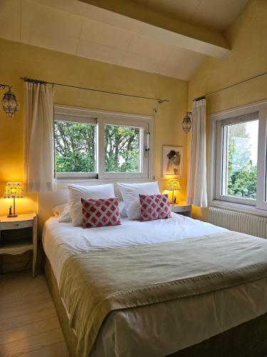 a bedroom with a large bed with two windows at La Terre d'Or in Beaune