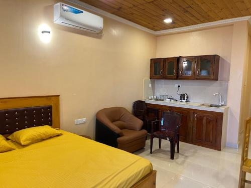 a bedroom with a bed and a chair and a kitchen at Palm Path Resort in Jaffna