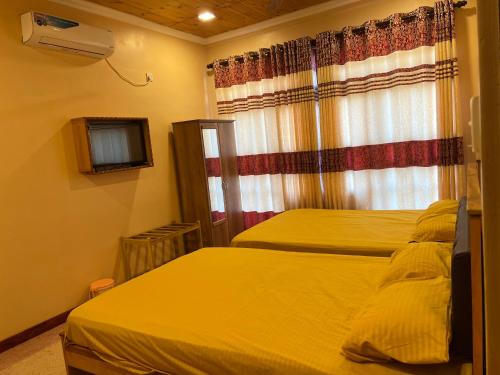 a bedroom with two beds and a window at Palm Path Resort in Jaffna