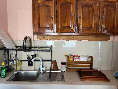 a kitchen with a sink and wooden cabinets at Palm Path Resort in Jaffna