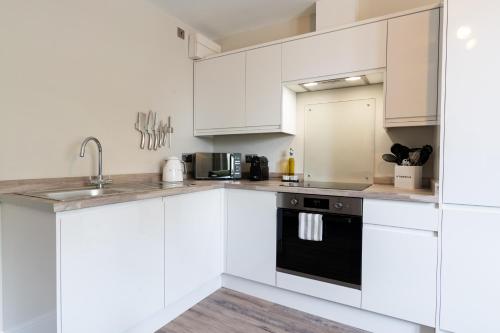 a kitchen with white cabinets and a black appliance at Wellington Place I Your Apartment in Bristol