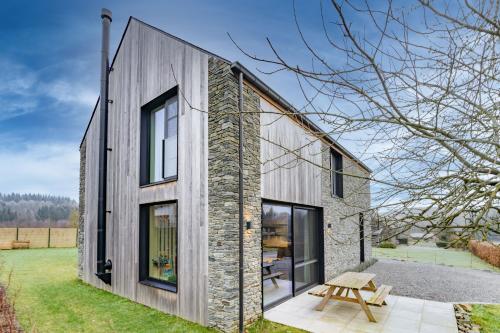 a house with a stone wall and windows at Nature'Hayette in Tenneville