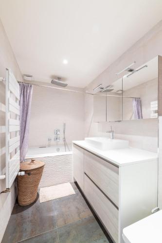 La salle de bains blanche est pourvue d'un lavabo et d'une baignoire. dans l'établissement PARIS PASSY Spacieux 2 Chambres Balcon, à Paris