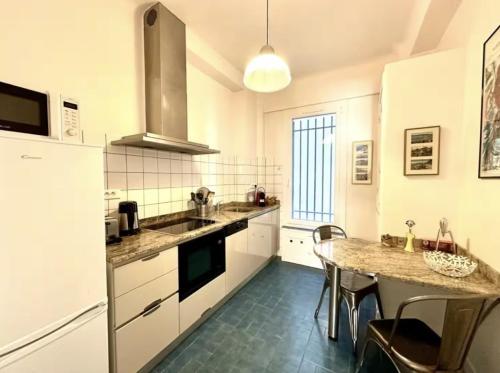 une cuisine avec des armoires blanches et une table avec des chaises dans l'établissement Charming apartment steps away from La Croisette and Palais de Festival, à Cannes
