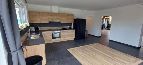a kitchen with wooden cabinets and a black refrigerator at Charming Chalet in Roisin, 400 m² with Terrace in Meaurain