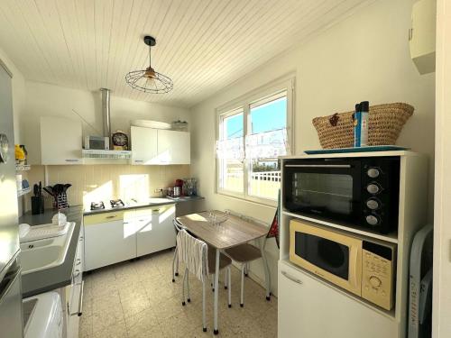 une cuisine avec une petite table et un micro-ondes dans l'établissement Appartement - Le Grau d'Agde, au Grau-dʼAgde