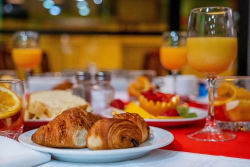 una mesa con un plato de cruasanes y zumo de naranja en Hôtel Sainte-Rose, en Lourdes