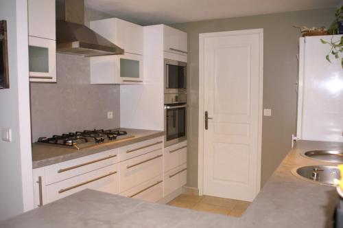 une cuisine avec des armoires blanches et un four à plaques de cuisson dans l'établissement Villa entre Mer et Cévennes, à Villetelle