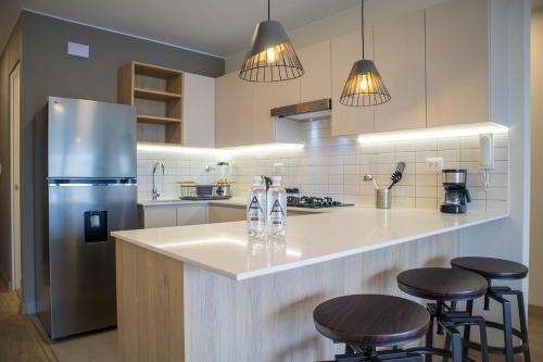 a kitchen with a refrigerator and some bar stools at Pod by Wynwood House in Lima