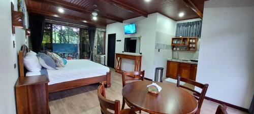 a bedroom with a bed and a table and a kitchen at Cabañas Refugio Verde Monteverde in Monteverde Costa Rica
