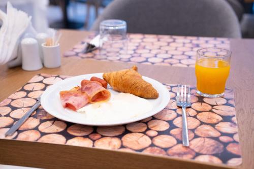 a plate of food on a table with a glass of orange juice at Volos Inn Hotel in Volos
