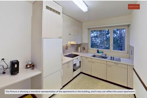 a kitchen with white cabinets and a sink and a window at Charming Apartment 15 Mins from City Life in Zürich