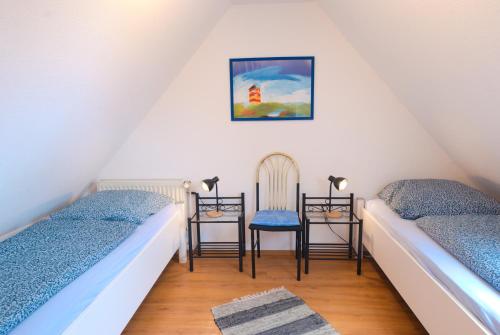 a attic room with two beds and two chairs at Ferienhaus Veldhoen in Norddeich