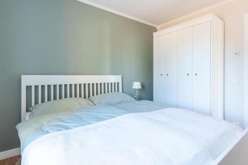 a white bedroom with a large bed and a white cabinet at Villa Vita Pärla in Timmernabben