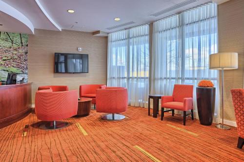a waiting room with red chairs and a flat screen tv at Courtyard by Marriott Harrisburg West/Mechanicsburg in Mechanicsburg