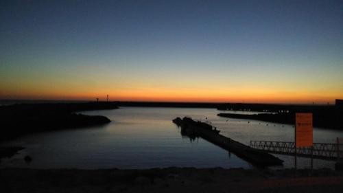 a body of water with a dock at sunset at Pousada Farol do Portinho in Vila Praia de Âncora