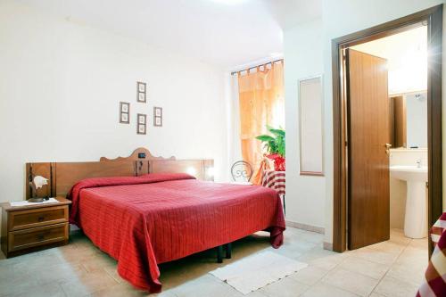 a bedroom with a red bed and a sink at Hotel Il Malandrone in Rosignano Marittimo