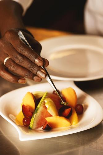 a person eating a plate of fruit on a table at Azalaï Hôtel Ouagadougou in Ouagadougou