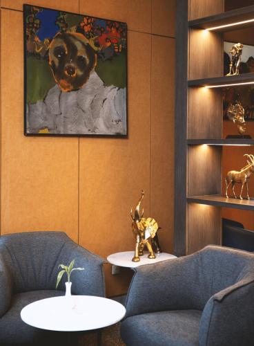 a lobby with two chairs and a table and a painting at Azalaï Hôtel Ouagadougou in Ouagadougou